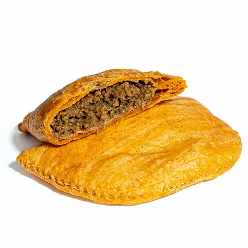 Two golden-brown Jamaican beef patties, one whole and one cut open revealing the savory minced meat filling.